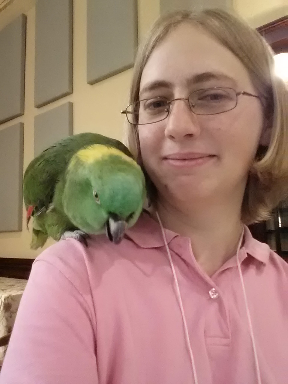 parrot sits on shoulder selfie; pink shirt